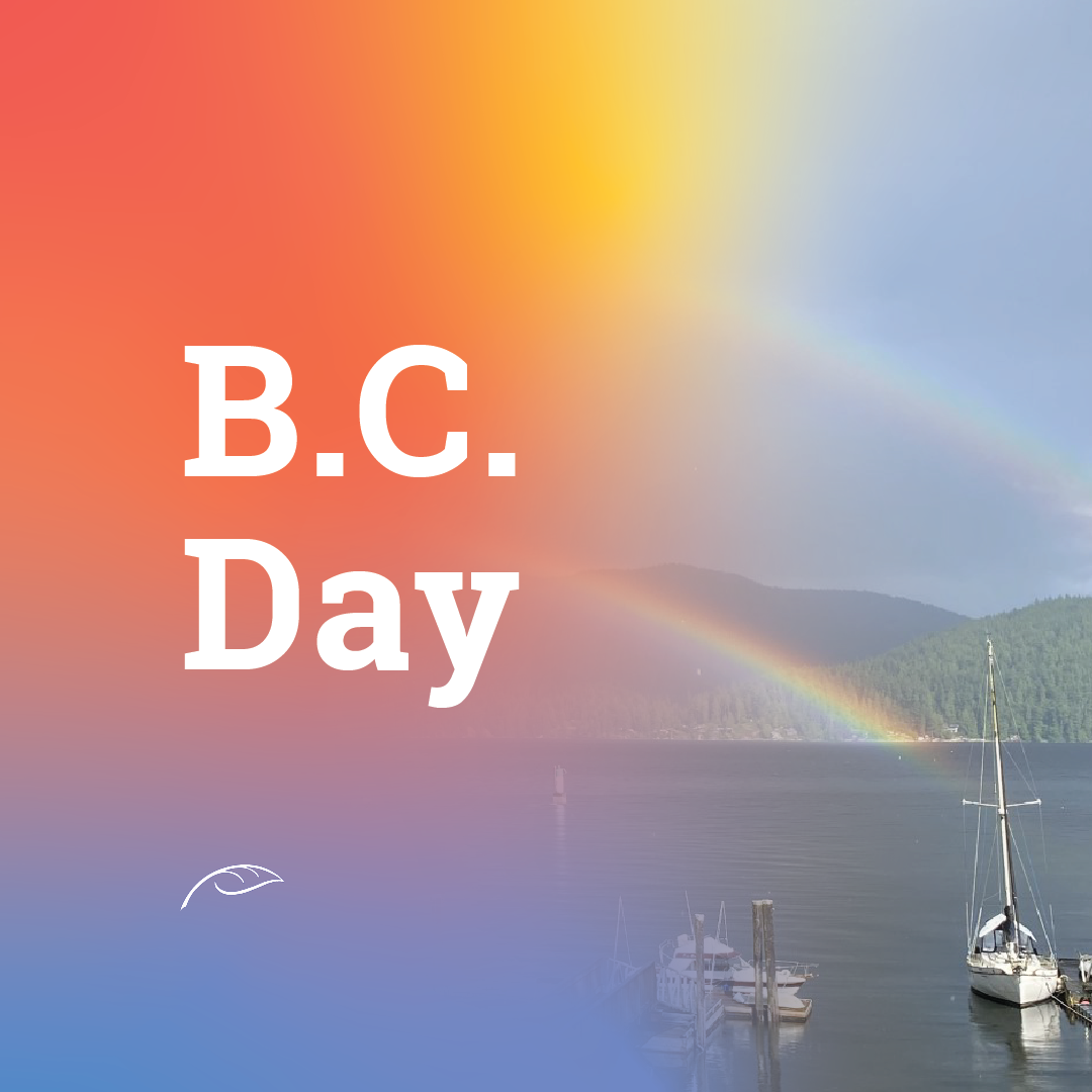 B.C. Day graphic featuring large white “B.C. Day” text over a scenic waterfront landscape. A rainbow stretches across the sky above forested mountains and calm water, with sailboats docked in the foreground.