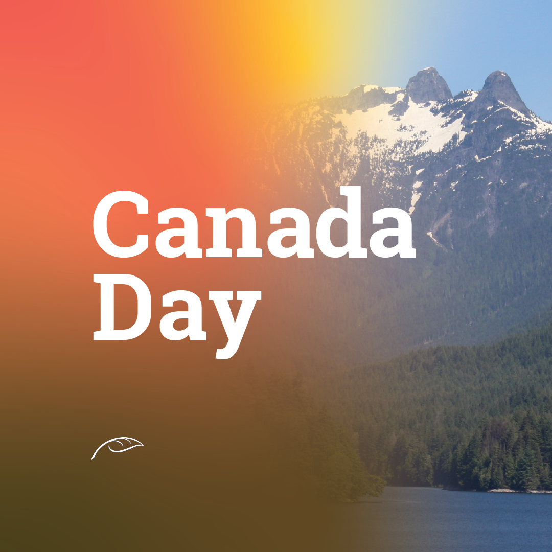 Canada Day graphic featuring large white “Canada Day” text over a scenic landscape of snow-capped mountains, dense evergreen forest, and a calm lake.